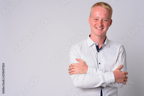 Portrait of happy young blonde businessman smiling with arms crossed © Ranta Images