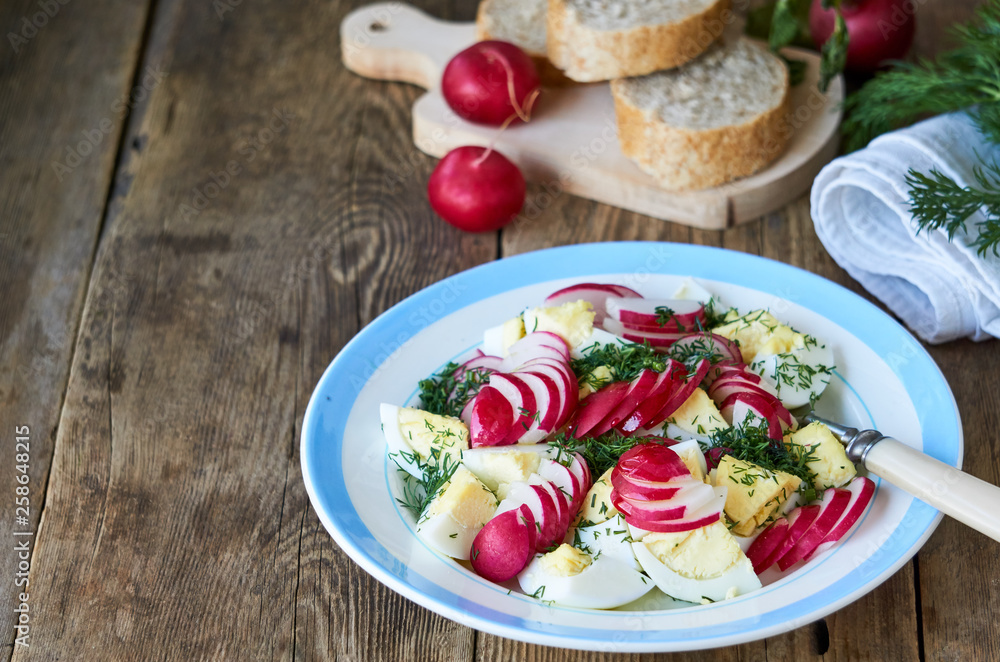 Vegetable salad with radishes, dill and eggs on a wooden background