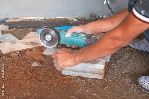 Worker cutting a tile using an angle grinder in home improvement and renovation.