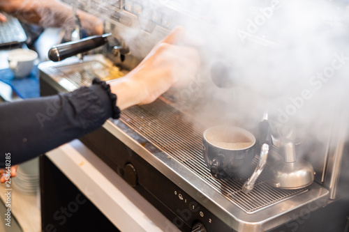 Close-up of barista or bartender's hand brewing coffee cup with machine maker.