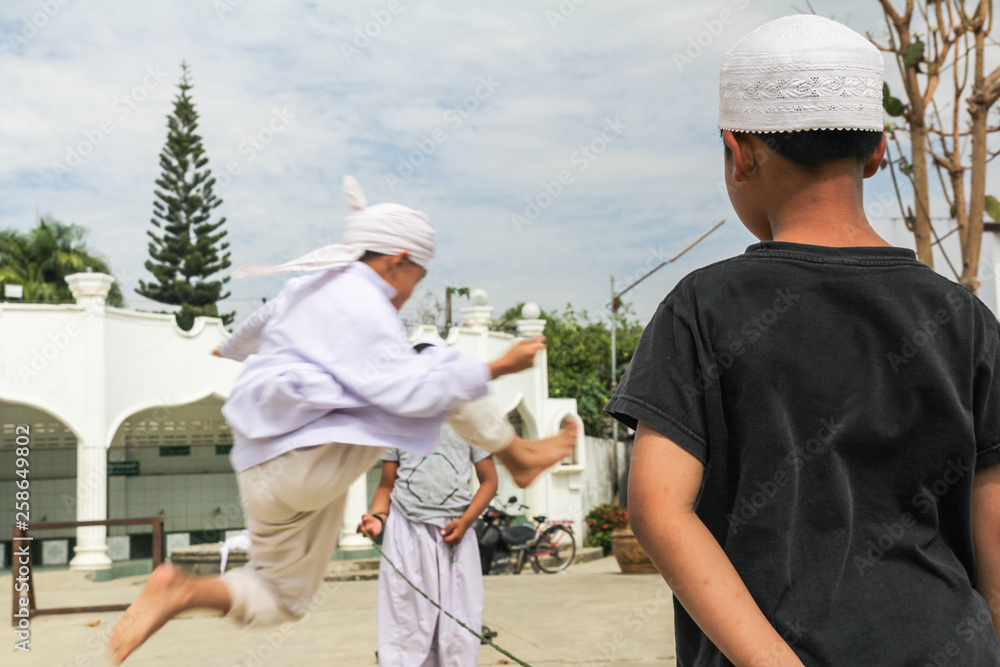 Group of Thai muslim boys enjoy play jumping rubber. Thai people life style.