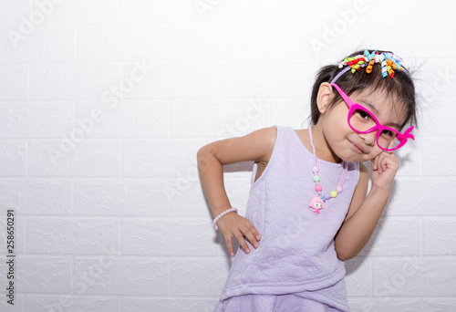Female asian child girl posing wacky thinking pose while wearing some accessories like crown, necklace and wearing purple dress