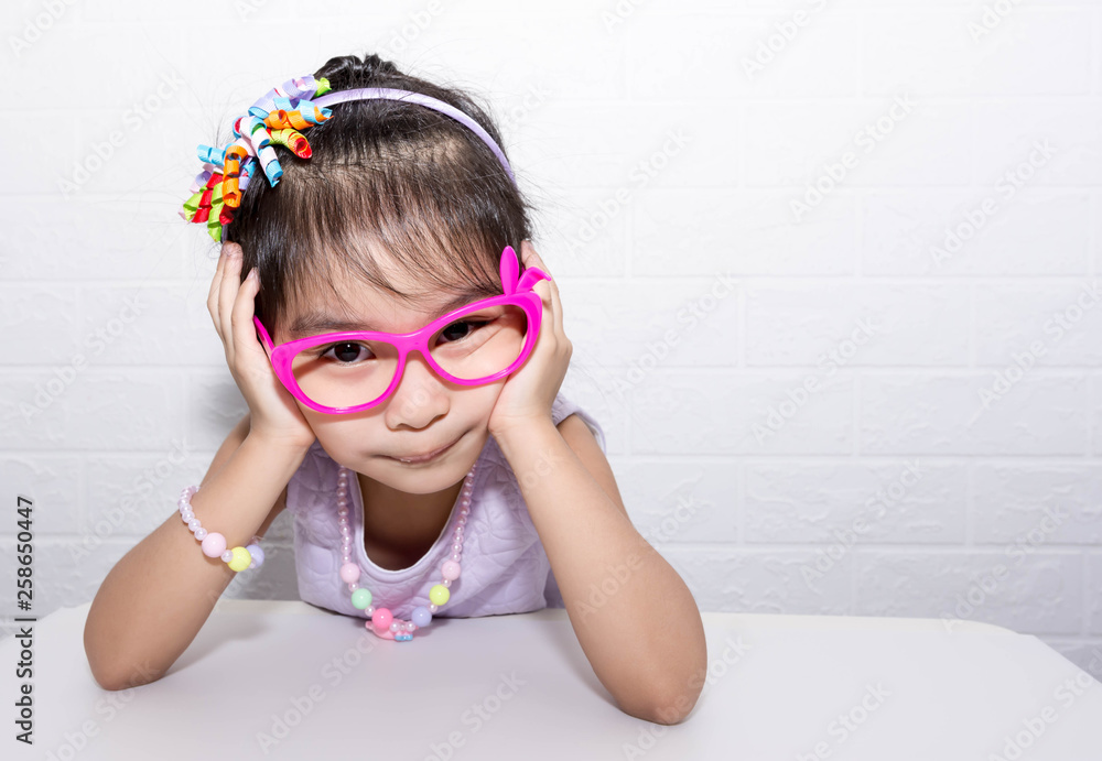 Female asian child girl posing wacky sad lonely pose while wearing some accessories like crown, necklace, pink eye glasses and wearing purple dress Female asian child girl posing wacky sad lonely pose while wearing some accessories like crown, necklace, pink eye glasses and wearing purple dress