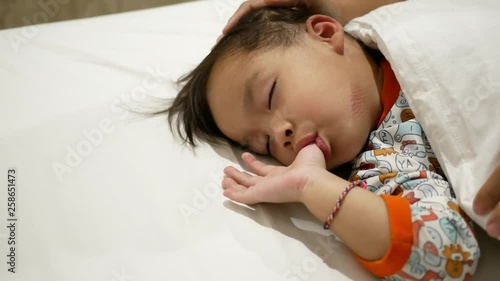 Asian mother is putting blanket on her daughter who is sleeping in the bed with love. Health care concept. photo