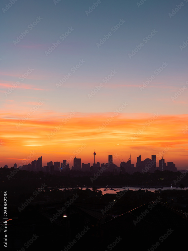 Sydney skyline with red orange sunset sky.