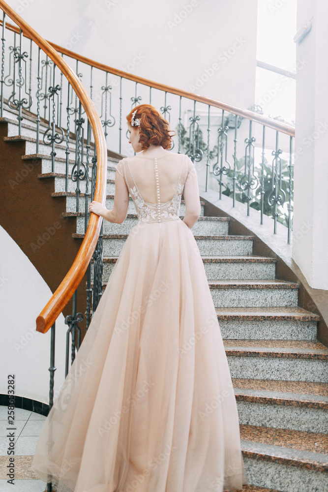 Fototapeta premium The bride is in an expensive hotel on the stairs. Wedding photo shoot in a beautiful dress.