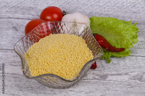 Raw couscous in the bowl served salad leaves, tomato and pepper photo