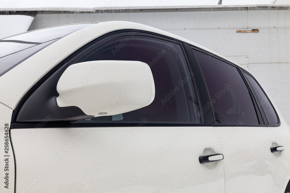 Front side mirror and window view of car in white color after cleaning before sale in a winter day and snow parking background