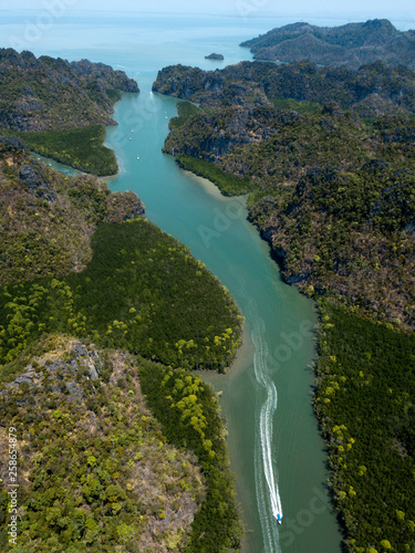 Aerial view of bay and river in Park Kilim Geoforest, Langkawi, Malaysia. Beautiful mountains, sea and trees around the river. Boat sailing on the river