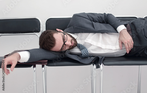 tired businessman sleeping on chairs in the office hallway