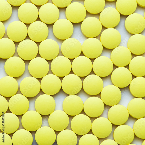 Small yellow pills on a white background close-up. © andreyphoto63