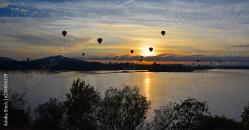 Hot air balloons flying in the air above Lake Burley Griffin, as part of the Balloon Spectacular Festival in Canberra. © katacarix