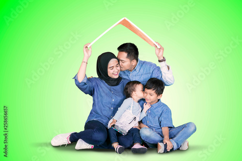 Family kisses each other under a roof symbol © Creativa Images