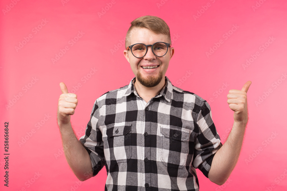 Youth, gesture and good concept - young man looks like a nerd show us thumbs up over the pink background Youth, gesture and good concept - young man looks like a nerd show us thumbs up over the pink background