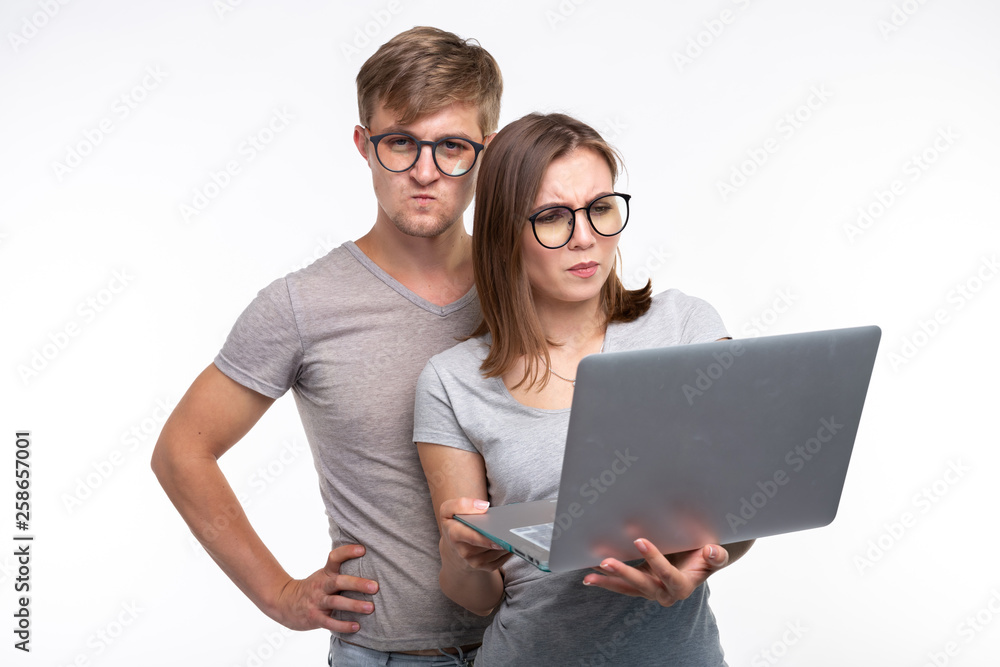 Nerds, study, people concept - a couple of students look at the netbook and look like scared on white background
