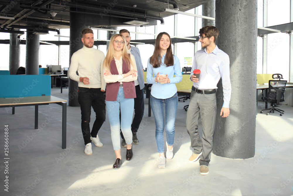 Naklejka premium Full length of young people in smart casual wear discussing business and smiling while walking through the office.