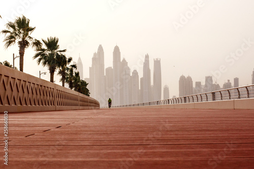 Canvas Print Morning walk, a man riding a bicycle on the road with a beautiful view of Dubai