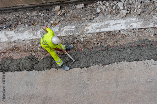 obrero esparciendo cemento sobre una zanja o obrero pavimentando o echando cemento para colocar una acera