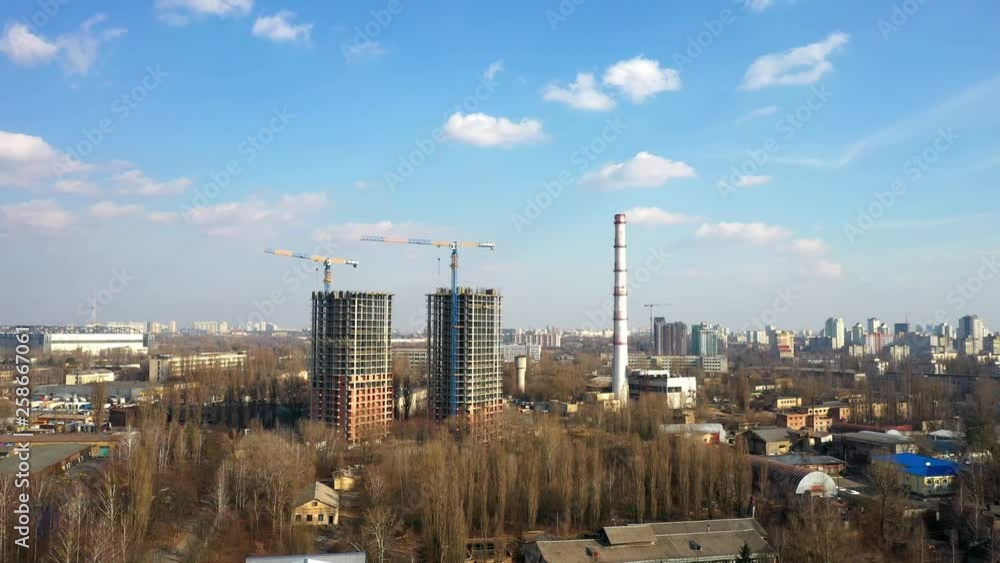 Drone aerial of new buildings being constructed next to old industrial chimney Drone aerial of new buildings being constructed next to old industrial chimney