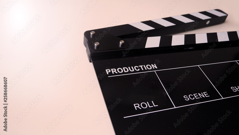 Clapper board or movie slate use in video production and cinema industry. It's black color on white background with flare light.