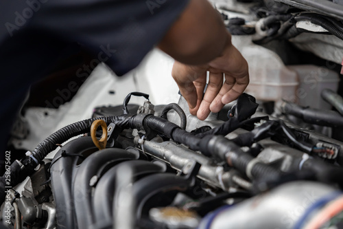 Hands of auto mechanic repairing car engine in garage. Maintenance car.