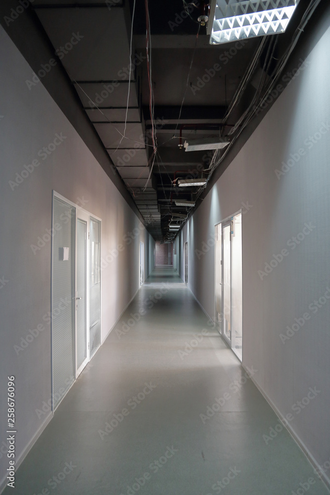 Fototapeta premium Długi wąski korytarz z drzwiami w biurze lub miejscu pracy