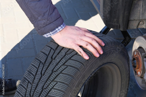 Male hand is changing tyre at car, close up. Wheel balancing or repair and change car tire. Automobile maintenance concept. © Ga_Na