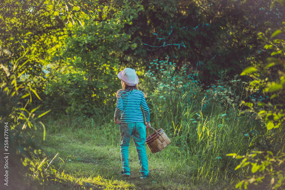 Young girl walking on a path through green woods carrying a birchbark basket Young girl walking on a path through green woods carrying a birchbark basket