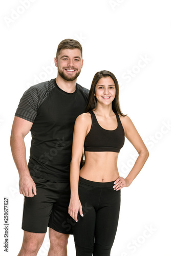 Young beautiful couple in black sportswear posing on white background