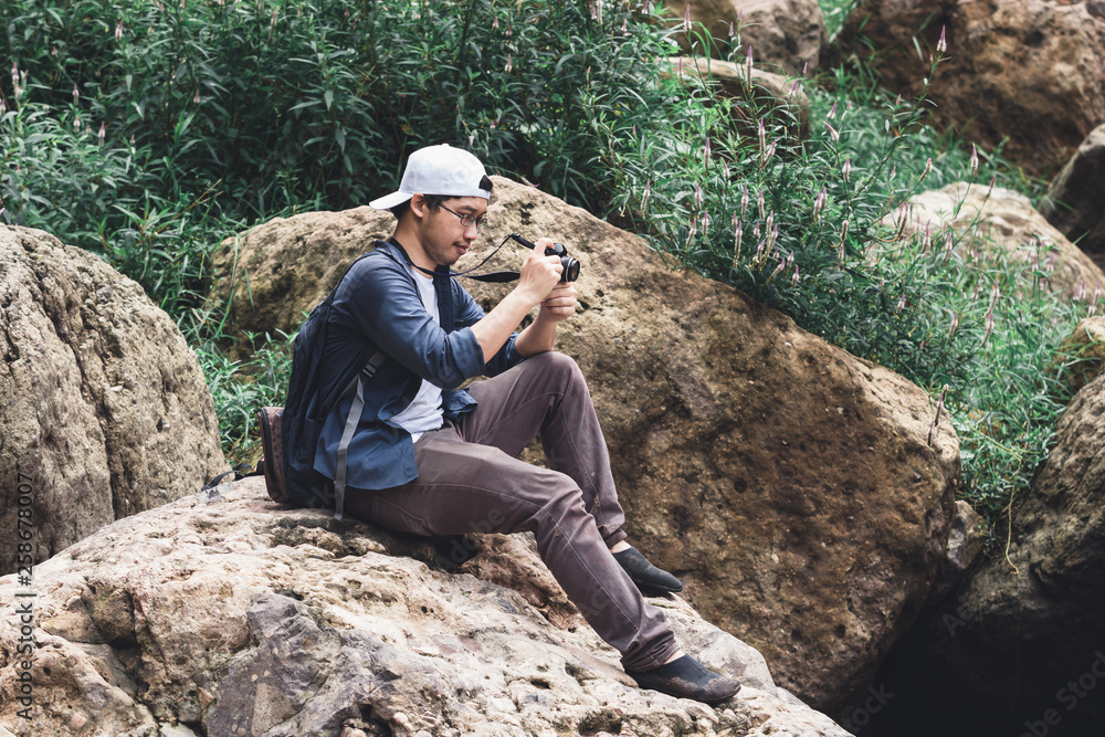 Young Asian traveler man taking photo outdoors scenic nature background. Lifestyle and relaxation concept. Young Asian traveler man taking photo outdoors scenic nature background. Lifestyle and relaxation concept.