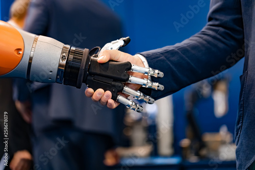Hand of a businessman shaking hands with a Android robot. © Andrei Armiagov