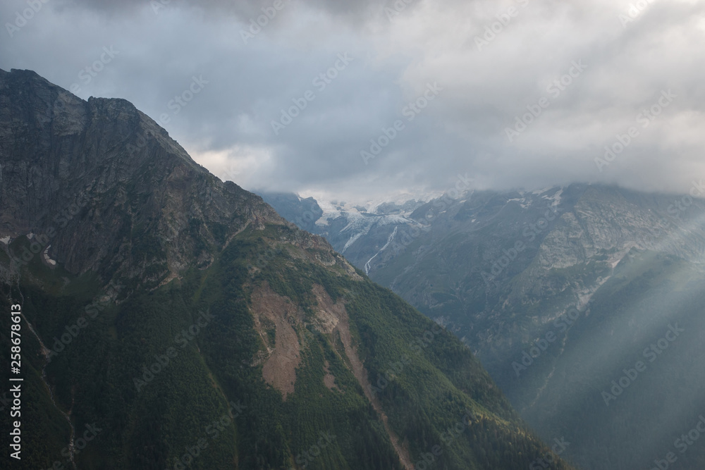 Panorama of misty mountains scene with dramatic sky in national park of Dombay