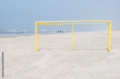 Yellow football goal on the beach.