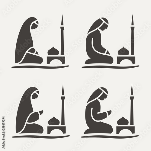 Traditionally clothed Muslim Arab man and woman making a supplication (Salah) while sitting on a praying rug