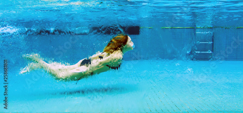 Woman underwater in a glass swimming pool