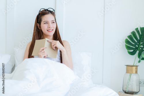 beautiful attractive asian woman enjoy reading book on bed portrait of asian long hair woman enjoy weekend activity white bedroom