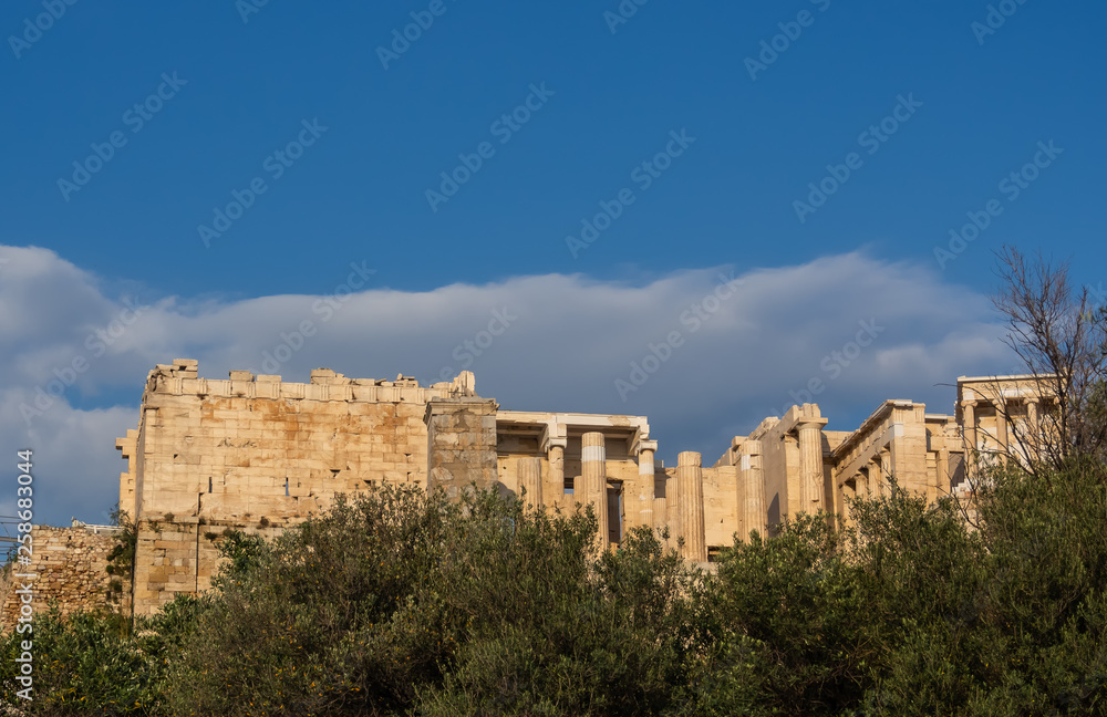 View of Propylaea entrance to Acropolis area on Athens, Greece against clear blue sky and greenery