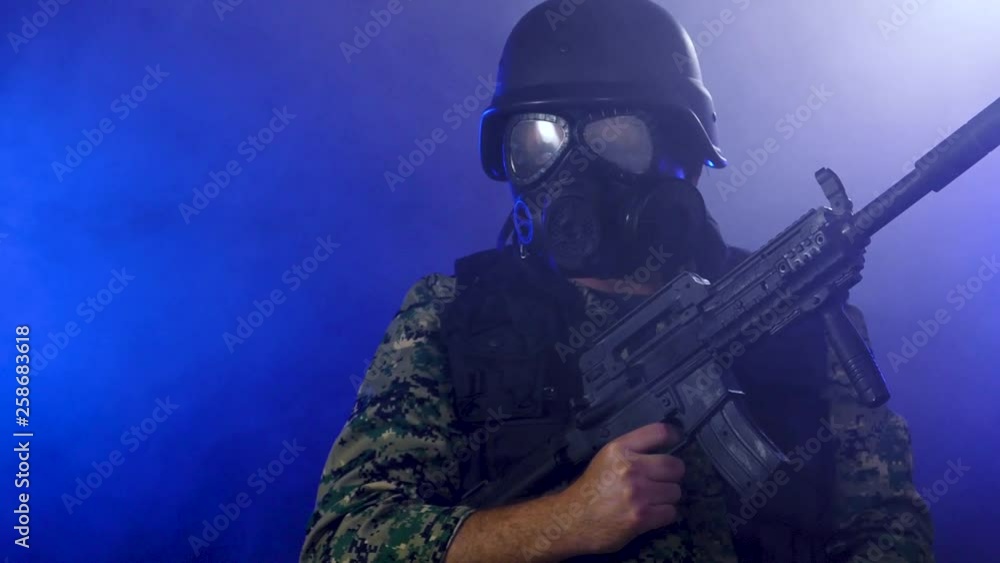 Soldier wearing gas mask holds rifle through smoke looking at camera Soldier wearing gas mask holds rifle through smoke looking at camera