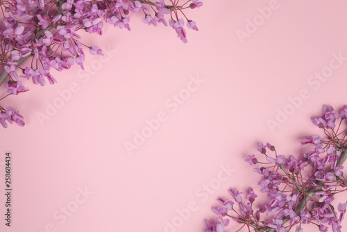 Flowers composition. Purple flowers and leaves on pastel pink background. Flat lay, top view, copy space