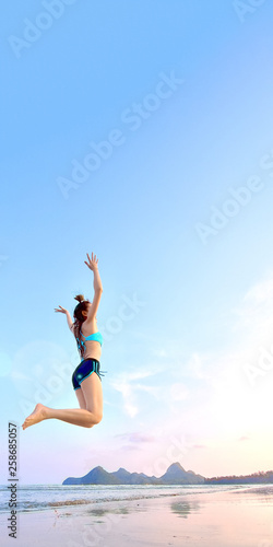 summer concept from asian woman in bikini is jumping on the beach with freedom for website where you place banner ads.
