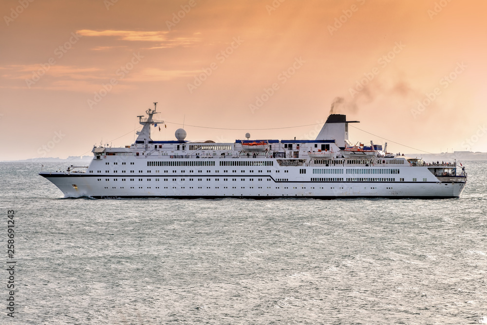Cruise ship sailing off the coast during sunset.