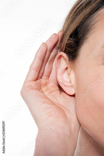 listening to sounds - woman with hand near ear - close up