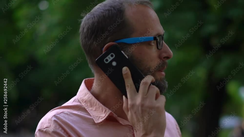 Handsome man talking on cellphone in city park Handsome man talking on cellphone in city park