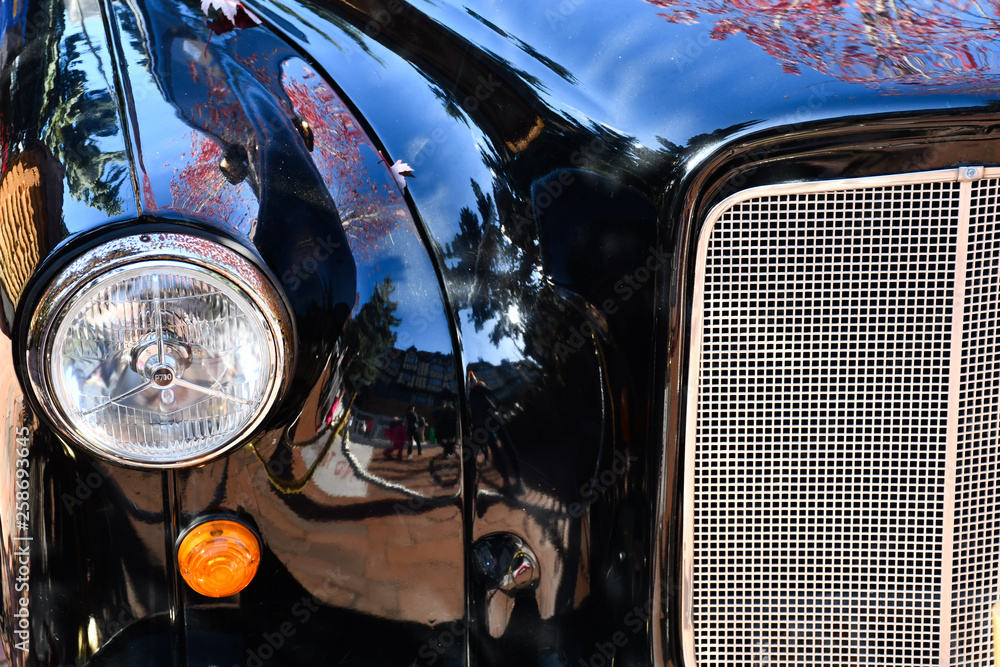 Shiny black classic car, close-up of front parts in detail, headlights, hoods and bumpers, classic car concept image.