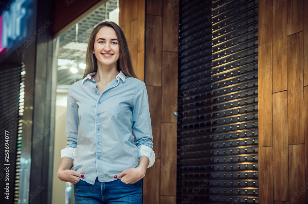 Beautiful brown-haired woman with long hair in a shirt, blue jeans in heels in the Mall Beautiful brown-haired woman with long hair in a shirt, blue jeans in heels in the Mall