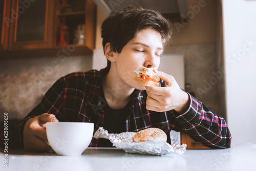 attractive man eat sandwich with cup of tea in hand