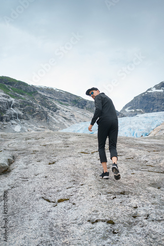 portrait of young traveler rock climber on the background of spellbinding landscape of Norwegian nature with high charming mountains and hills