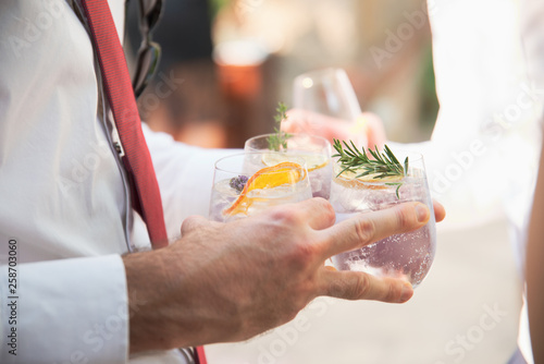 carrying a trio of gin cocktails at a formal celebration