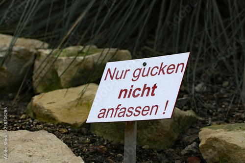 Schild mit deutschen Text - nur gucken nicht anfassen - in einem botanischen Garten