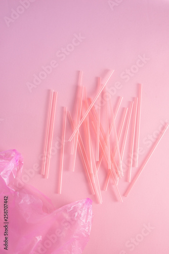 Closeup of colorful plastic waste in a pink garbage bag as recyclable single use cutlery pollution junk concept isolated on pink background